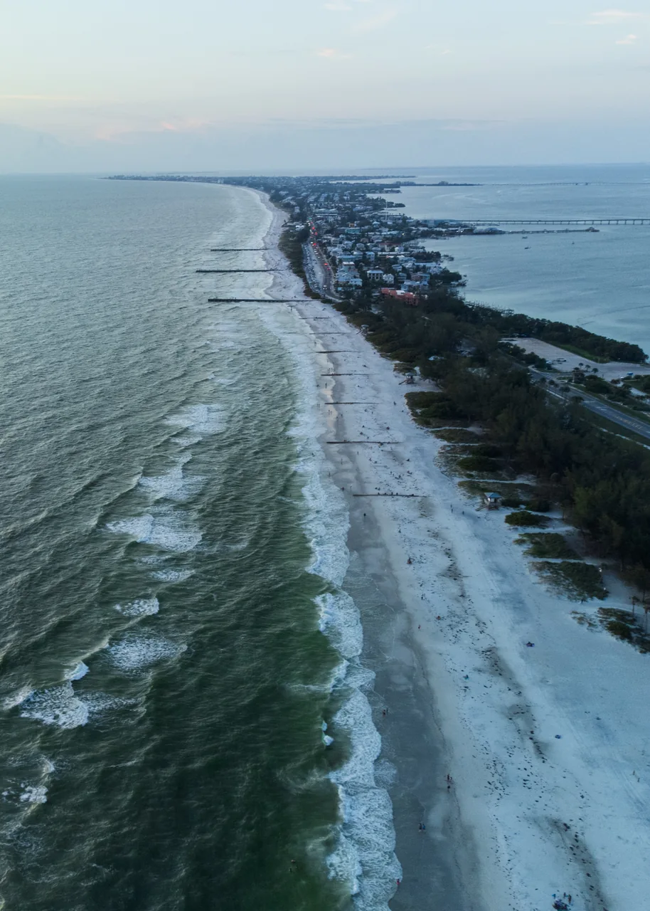 A long coastline curves into the distance beneath a pale evening sky.
