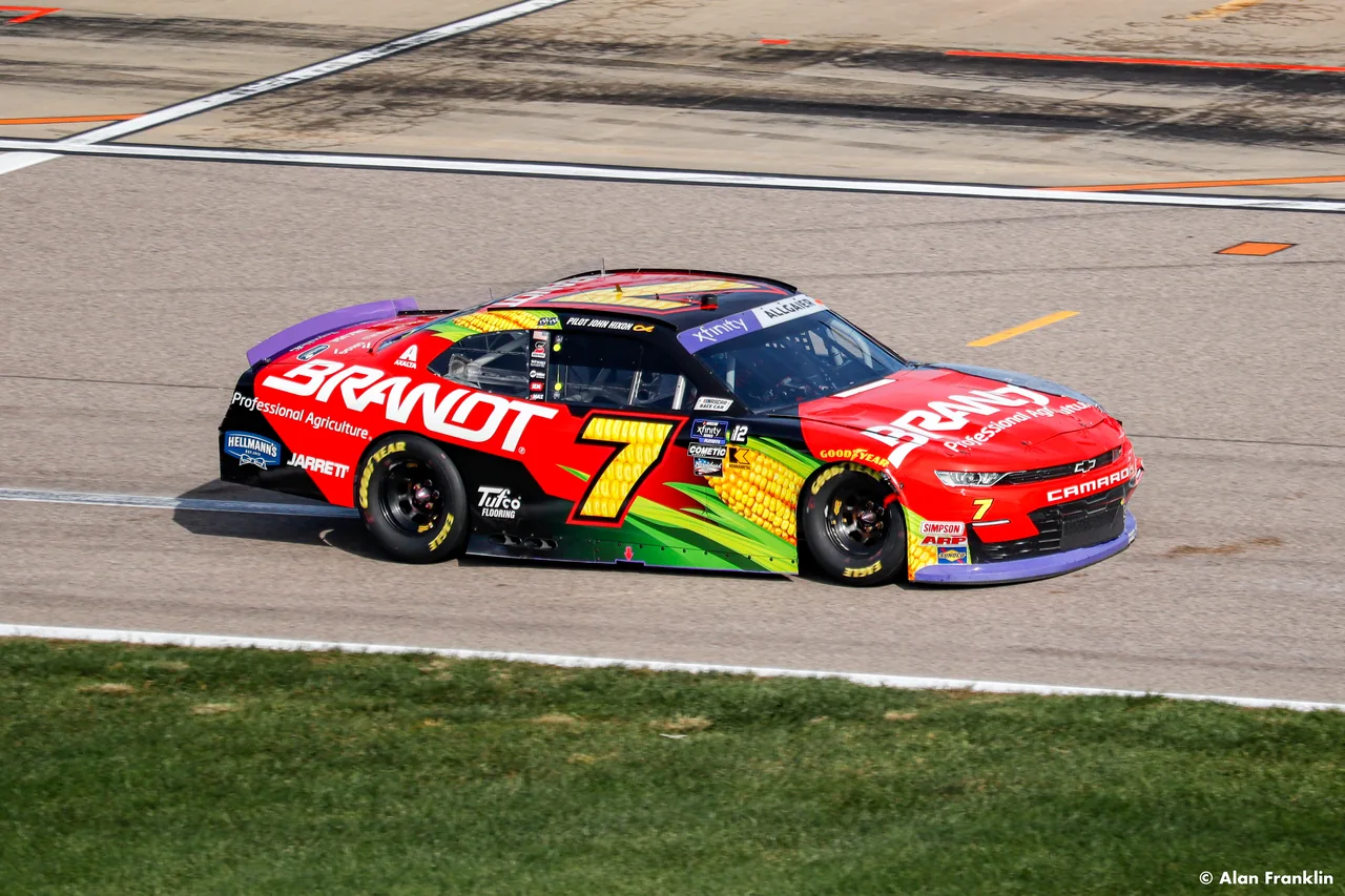A red number seven stock car races along the track.