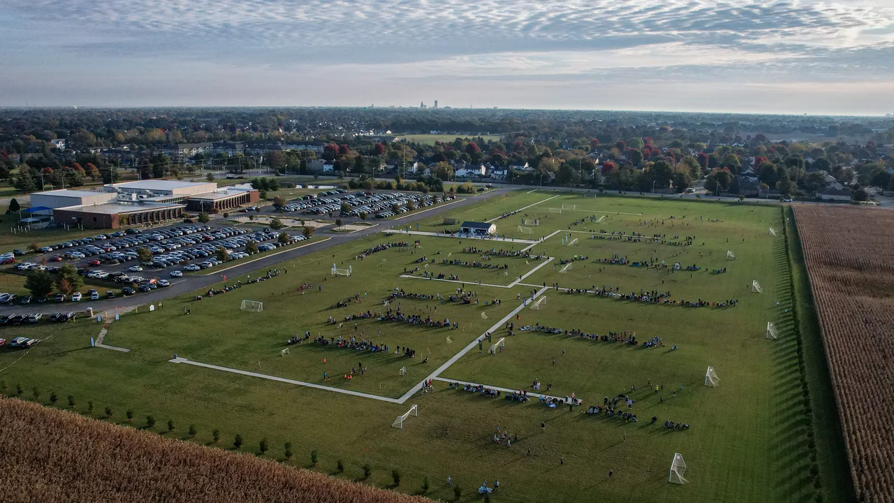 An aerial view of busy soccer fields and the YMCA of Springfield beneath a patterned autumn sky.